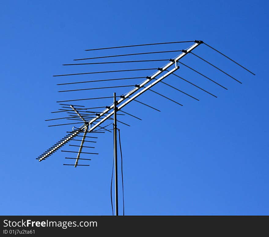 Old fashion aerial television antenna isolated against blue sky.