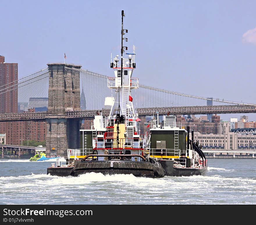 Tugboat going up the East River toward the Brooklyn Bridge with Midtown Manhattan in the background. Tugboat going up the East River toward the Brooklyn Bridge with Midtown Manhattan in the background.