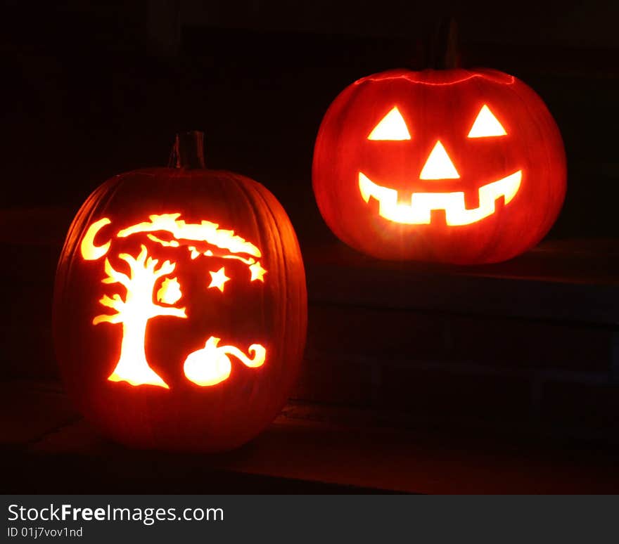 Two pumpkins illuminated from within at night for Halloween.