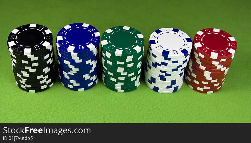 Five color poker casino stacks over green table