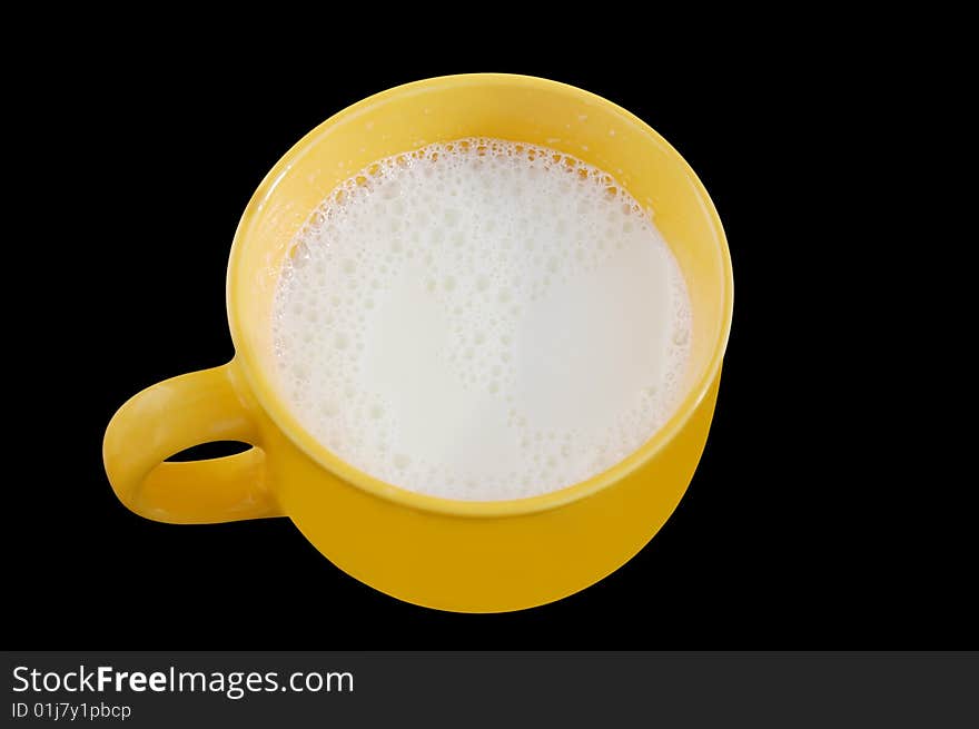 Fresh milk in big yellow cup on black background.