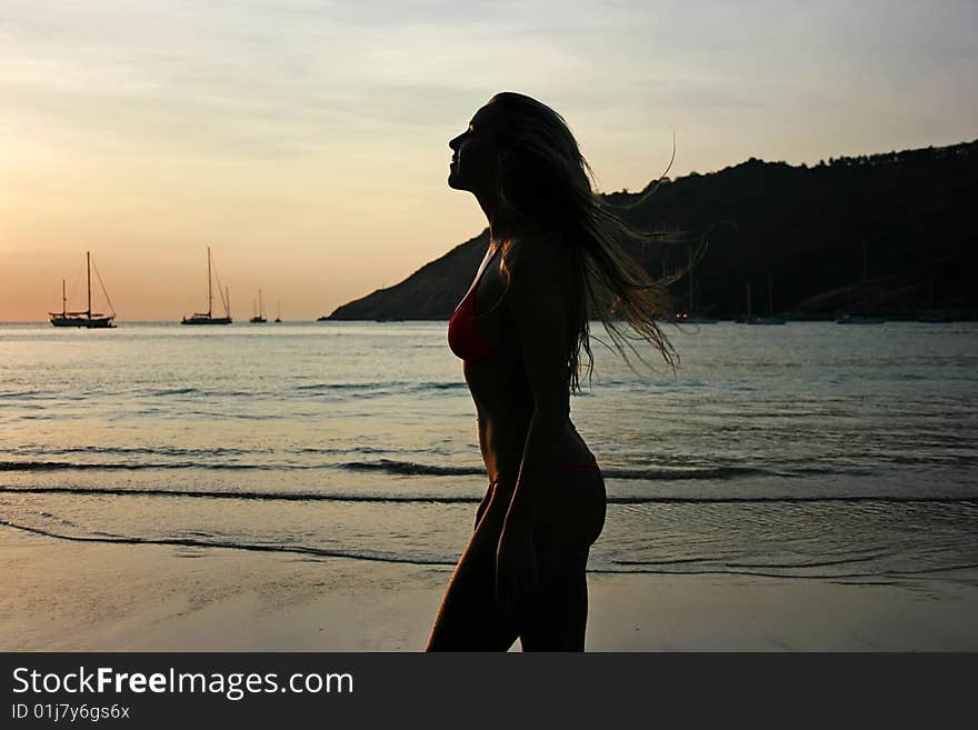 Silhouette of a beautiful young blonde girl on the beach