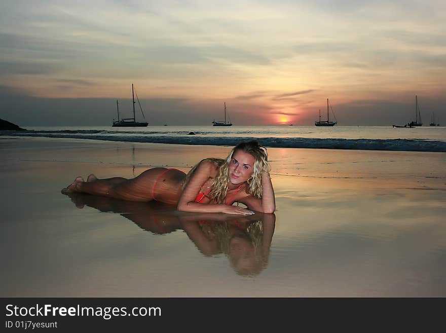 Woman lying on the sand beach at sunset. Woman lying on the sand beach at sunset