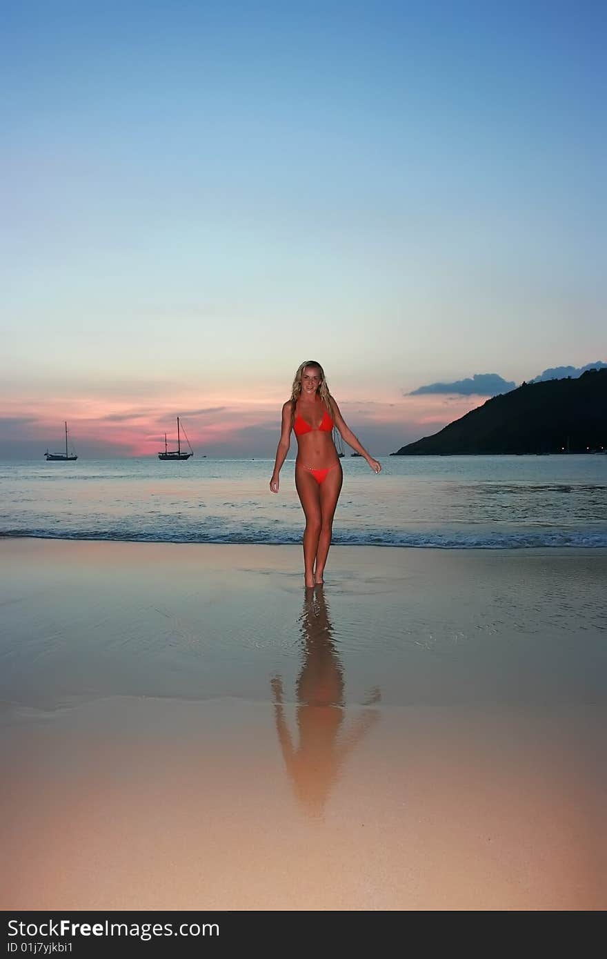 Girl standing on the sunset beach in thailand