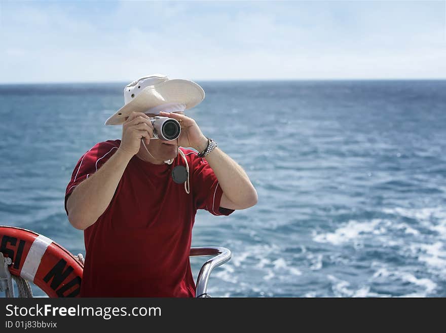 A middle aged man takes photos from a boat. A middle aged man takes photos from a boat