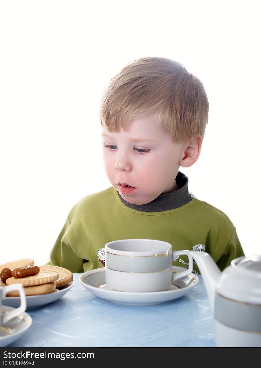 The little boy drinks tea with cookies. The little boy drinks tea with cookies