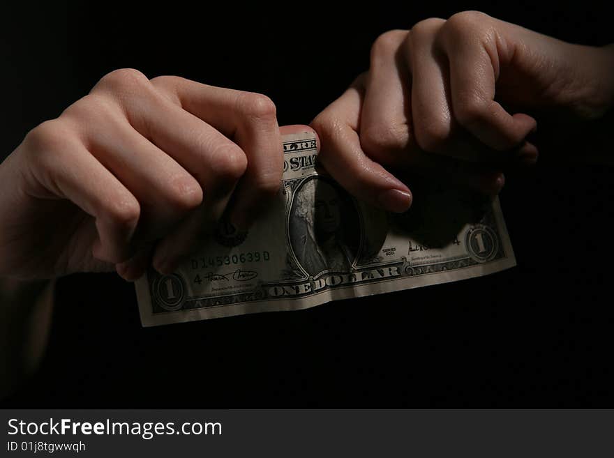 Close-up of human hands tearing dollar banknote.