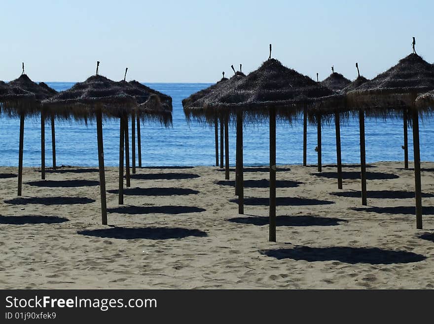 On a beach. sunshades. in the background the sea. On a beach. sunshades. in the background the sea