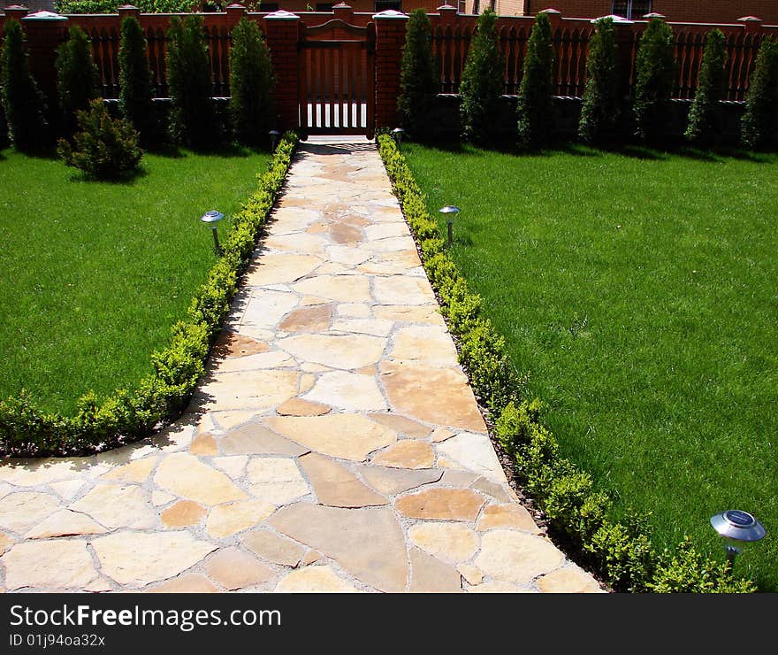 Garden stone path with grass growing up between the stones