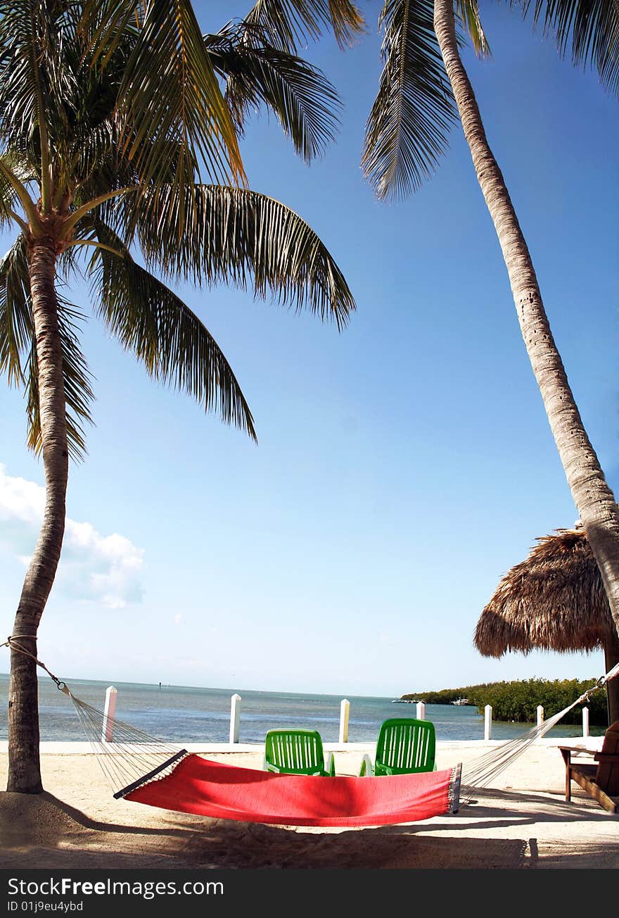 Peaceful view of a beach resort with a colorful hammock in the foreground. Peaceful view of a beach resort with a colorful hammock in the foreground