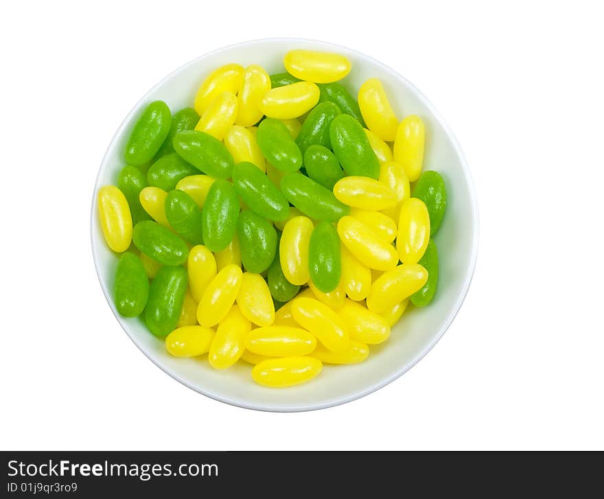 A bowl of green and yellow jelly beans isolated on a white background