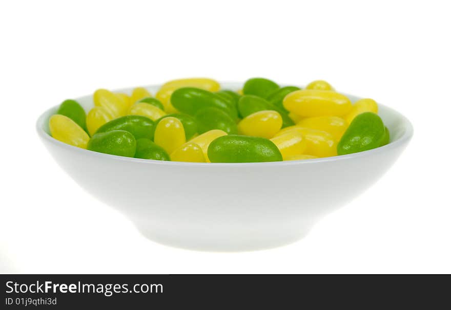 A bowl of green and yellow jelly beans isolated on a white background