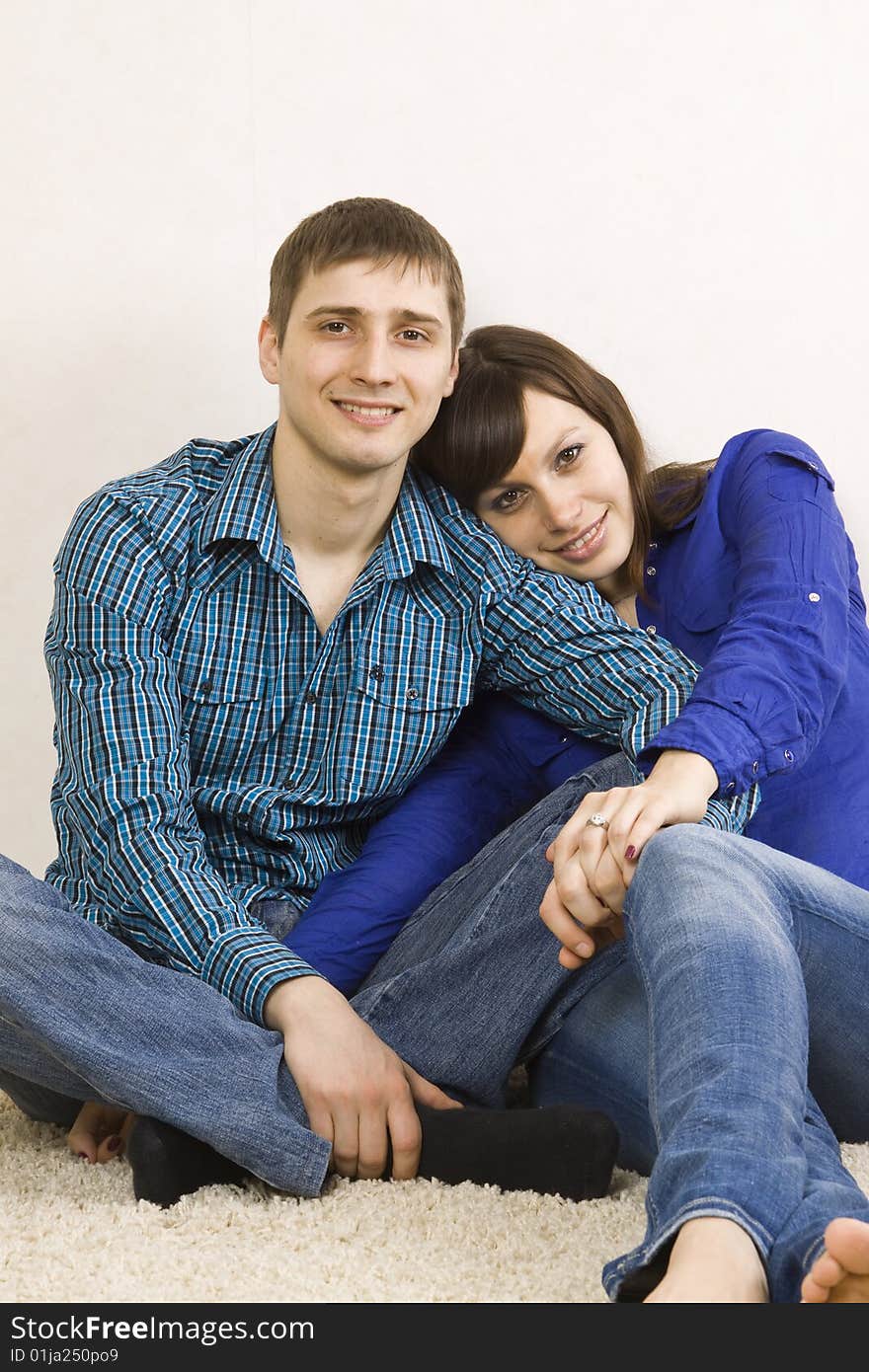 A young couple sitting on the floor in their living room.