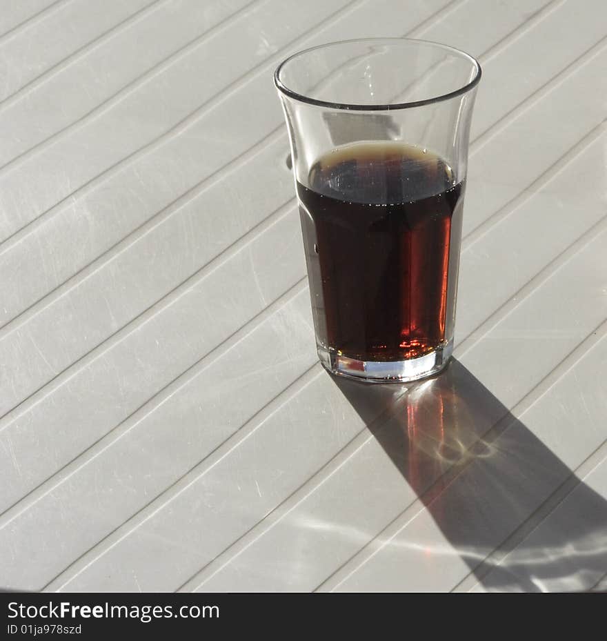 A half glass of coke drink on a white table