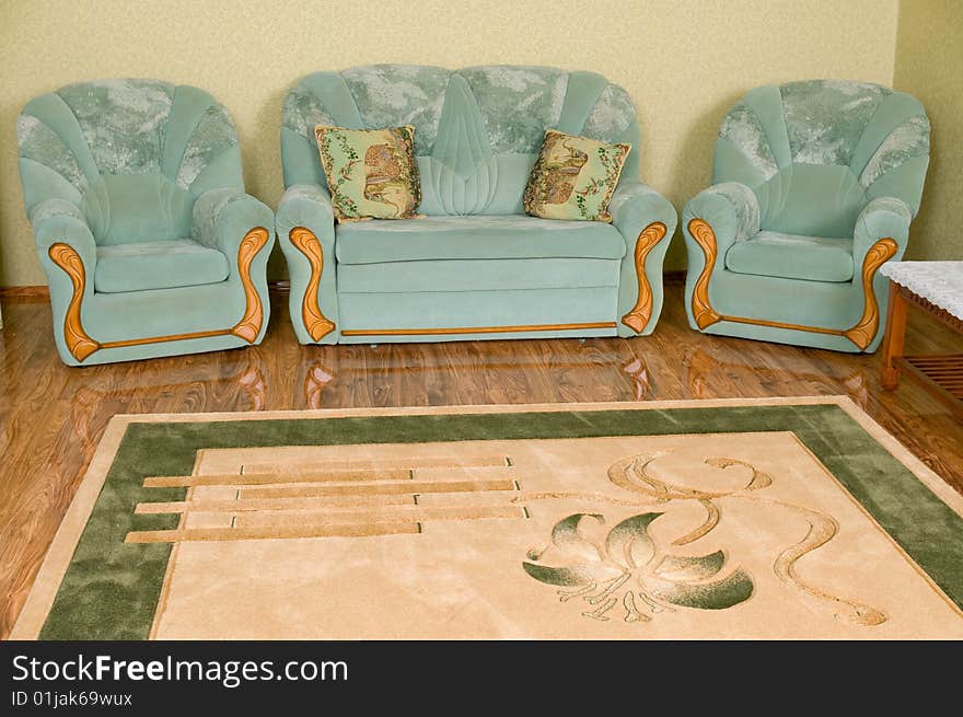 Interior of a drawing room of a room - in a shot the big sofa, two pillows, two armchairs and a beautiful carpet on a floor. Interior of a drawing room of a room - in a shot the big sofa, two pillows, two armchairs and a beautiful carpet on a floor.