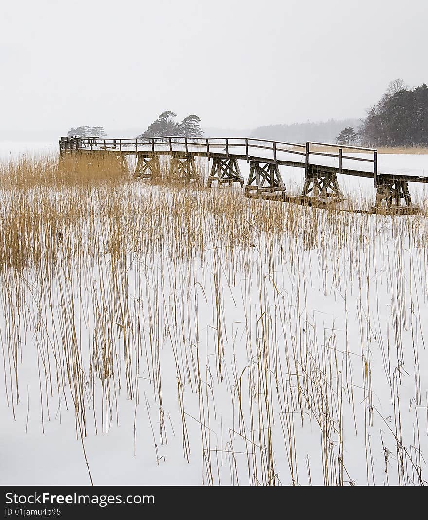 Old bridge on winter lake