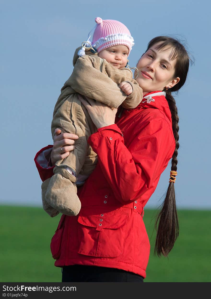 Little baby with mom on green grass and blue sky background