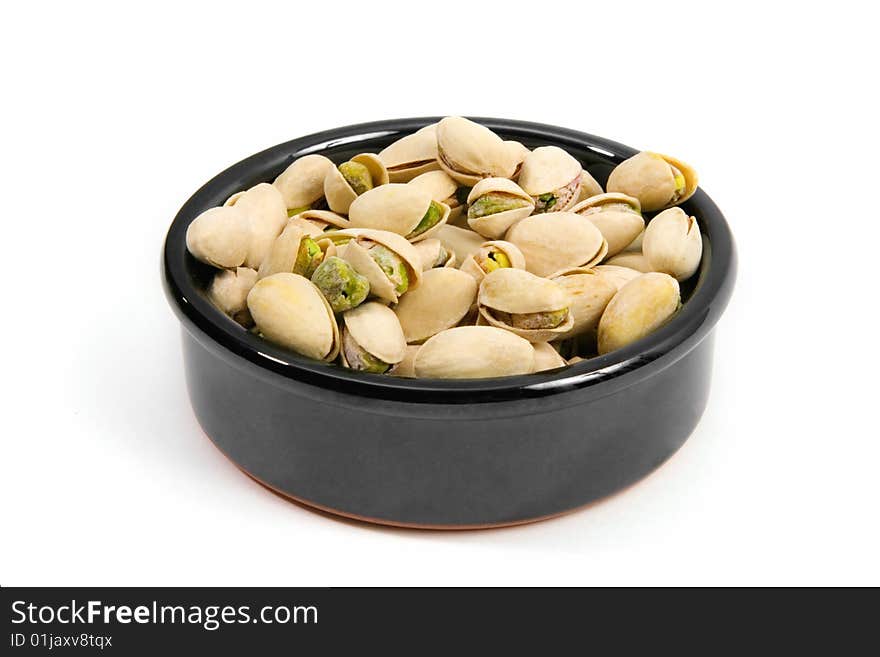 Pistachios in a ceramic bowl isolated on a white background.