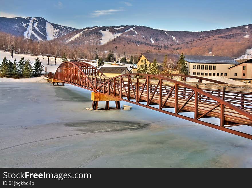 View of a framed bridge leading to a ski resort in high dynamic range.