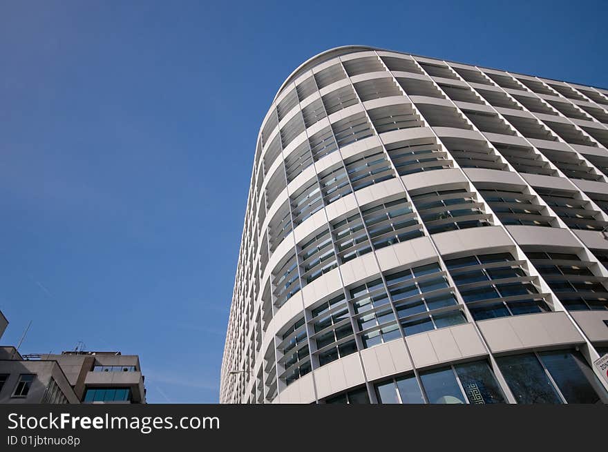 Photograph of a round corner of a smart looking building, shot against a clear blue sky. Photograph of a round corner of a smart looking building, shot against a clear blue sky.