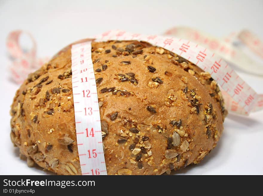 A whole-grain roll with a measuring tape. A whole-grain roll with a measuring tape.