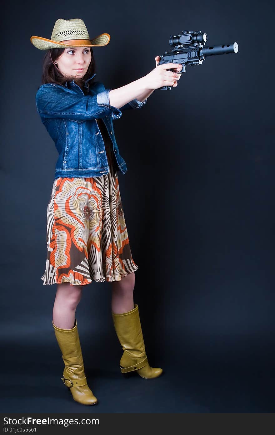 Girl in a cowboy's hat with the big pistol against a dark background. Girl in a cowboy's hat with the big pistol against a dark background