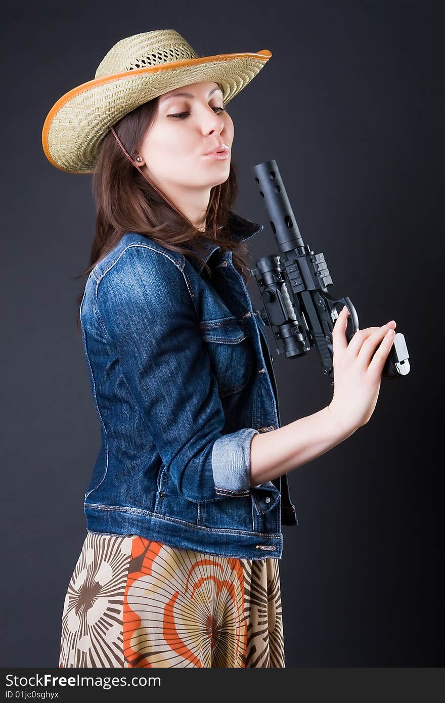 Girl in a cowboy's hat with the big pistol against a dark background. Girl in a cowboy's hat with the big pistol against a dark background