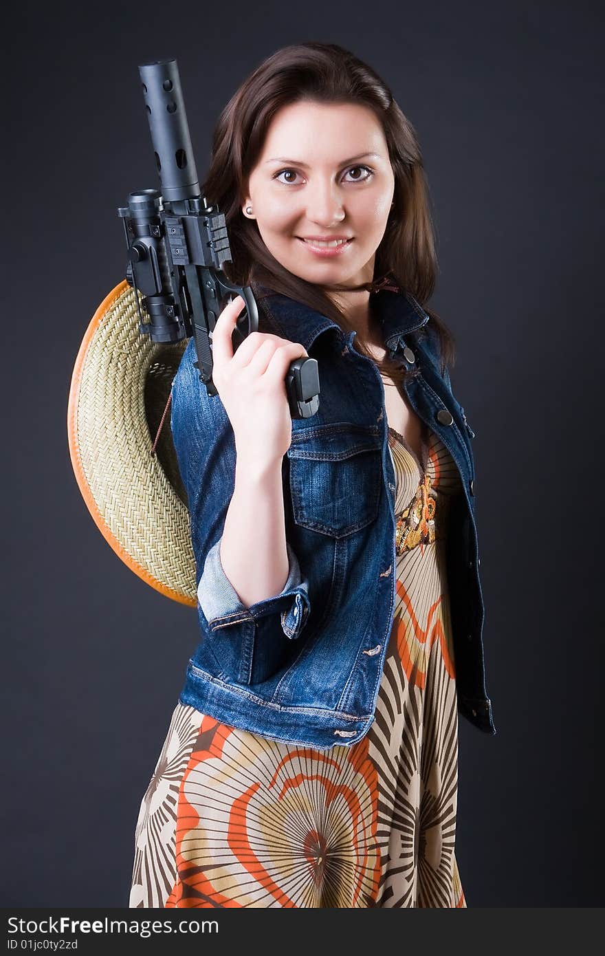 Girl in a cowboy's hat with the big pistol against a dark background. Girl in a cowboy's hat with the big pistol against a dark background