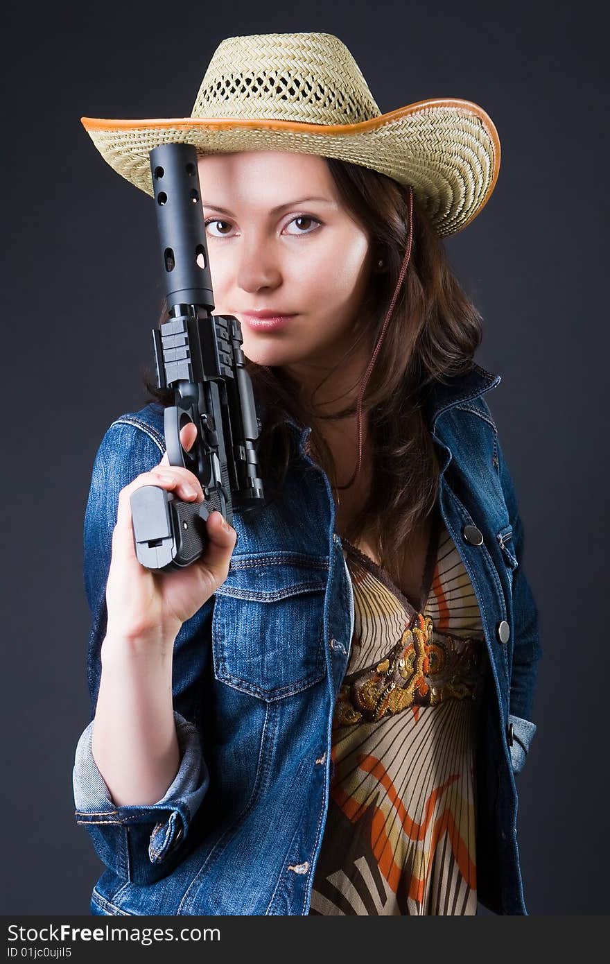 Girl in a cowboy's hat with the big pistol against a dark background. Girl in a cowboy's hat with the big pistol against a dark background