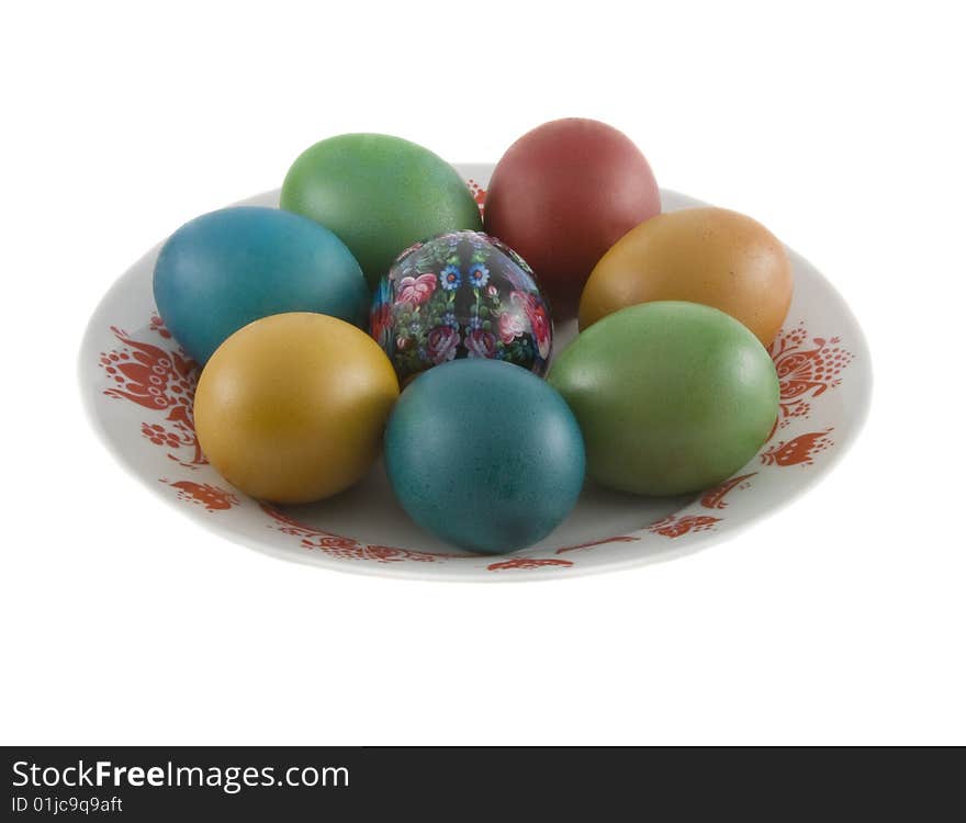 The easter decorated eggs lying in white porcelain plate with a red ornament