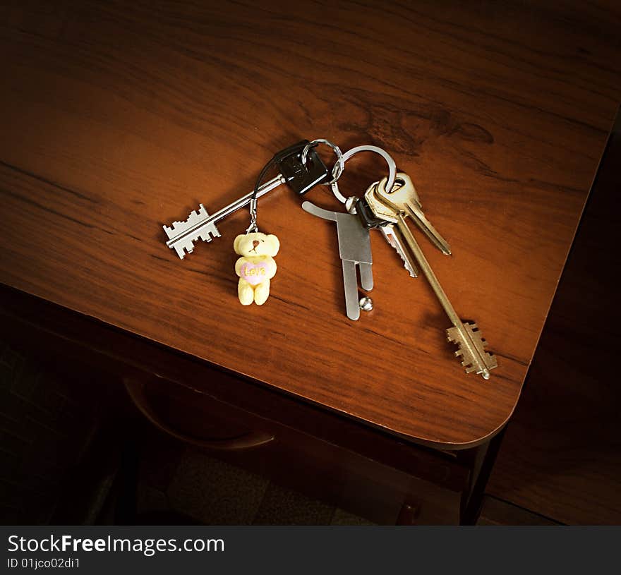 A bunch of keys with a soccer player and a teddy bear trinkets. A bunch of keys with a soccer player and a teddy bear trinkets