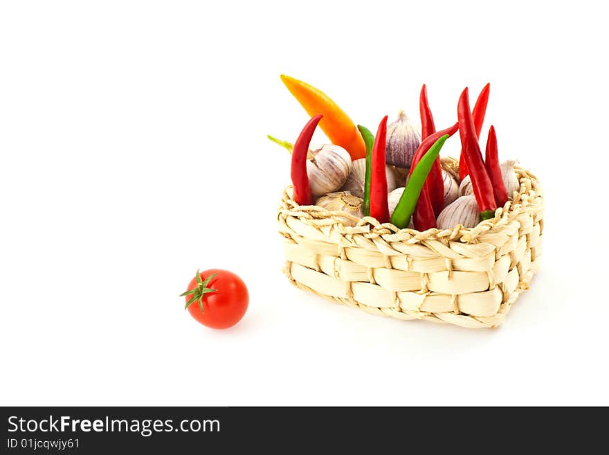 Tomato, pepper and garlic in a basket on a white background