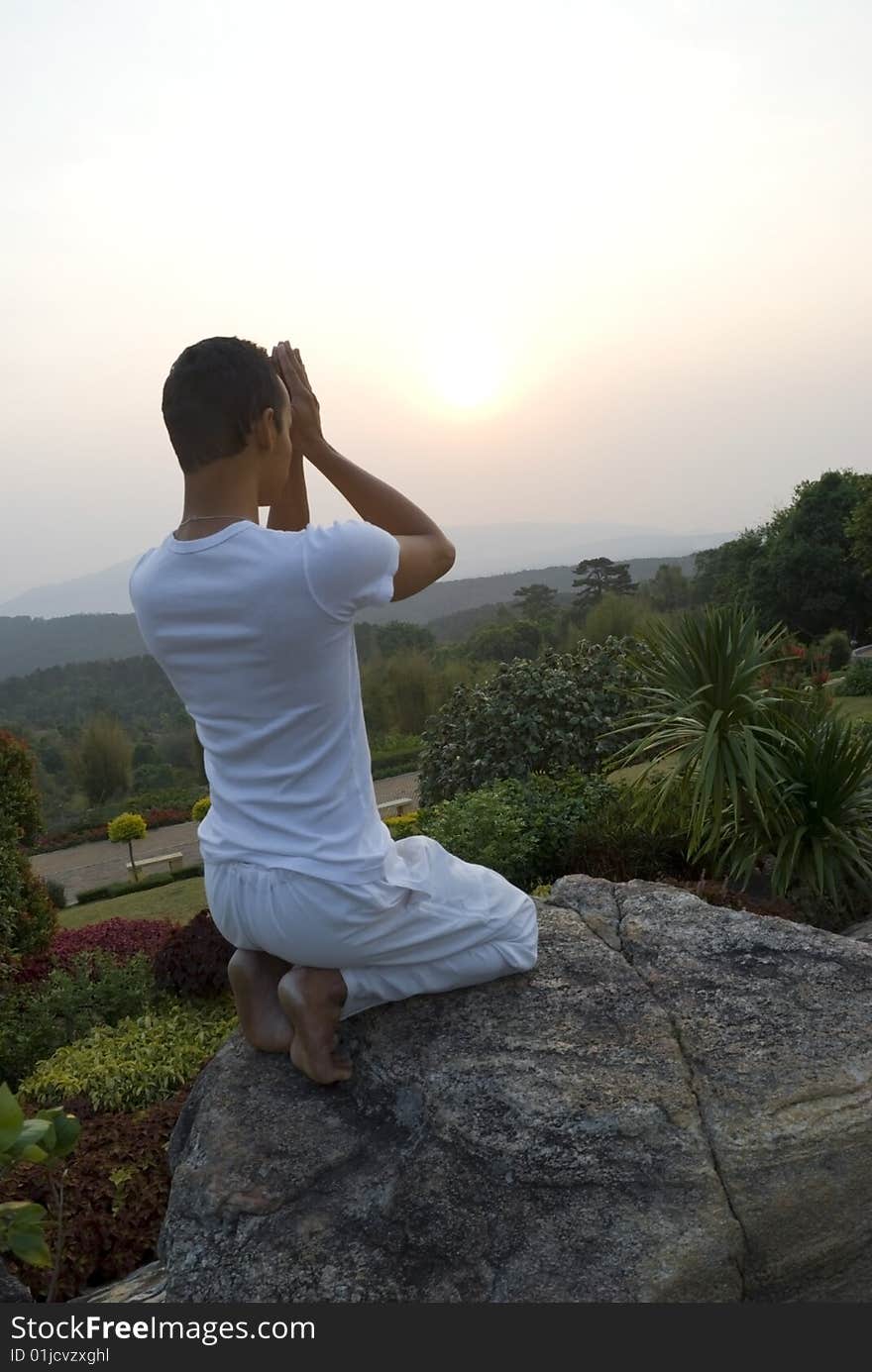 A man welcoming the sun with prayer and yoga movements on a mountain