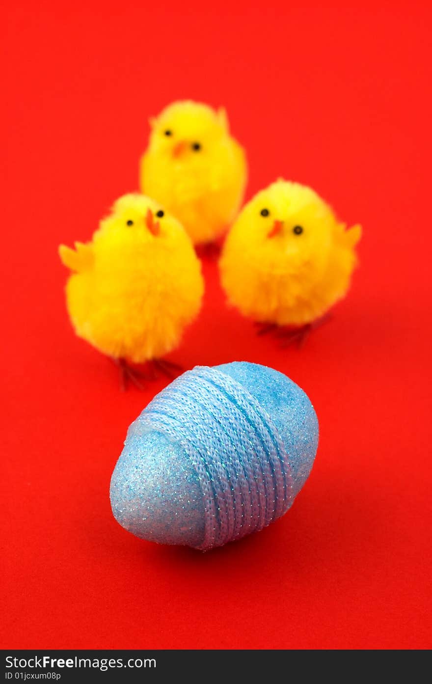 Blue Easter egg and three chicks isolated on red. Shallow depth of field. Focus on egg. Blue Easter egg and three chicks isolated on red. Shallow depth of field. Focus on egg.