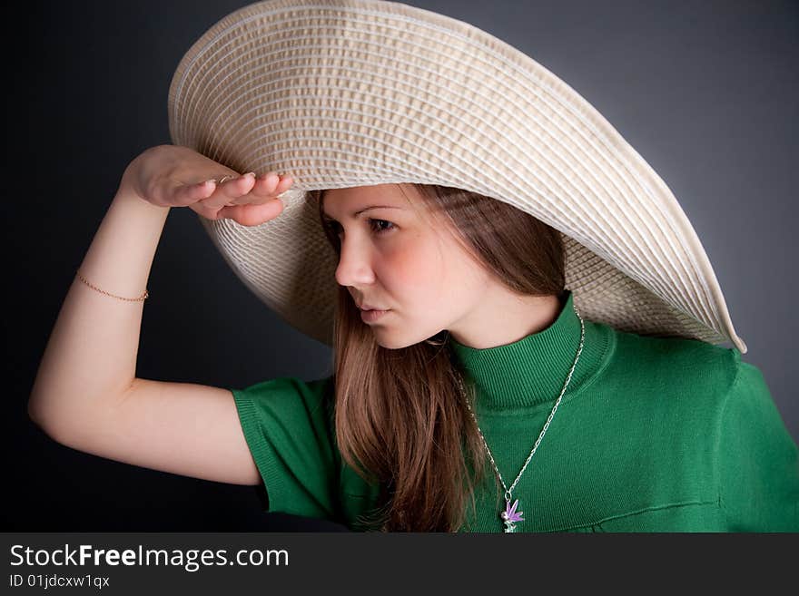 Funny young cutey in a green dress with a big straw hat is looking to the horizont. Funny young cutey in a green dress with a big straw hat is looking to the horizont