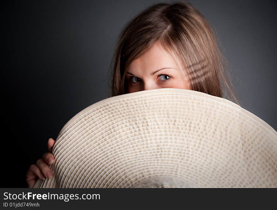 Pretty young girl is hiding behind the big straw hat. Pretty young girl is hiding behind the big straw hat