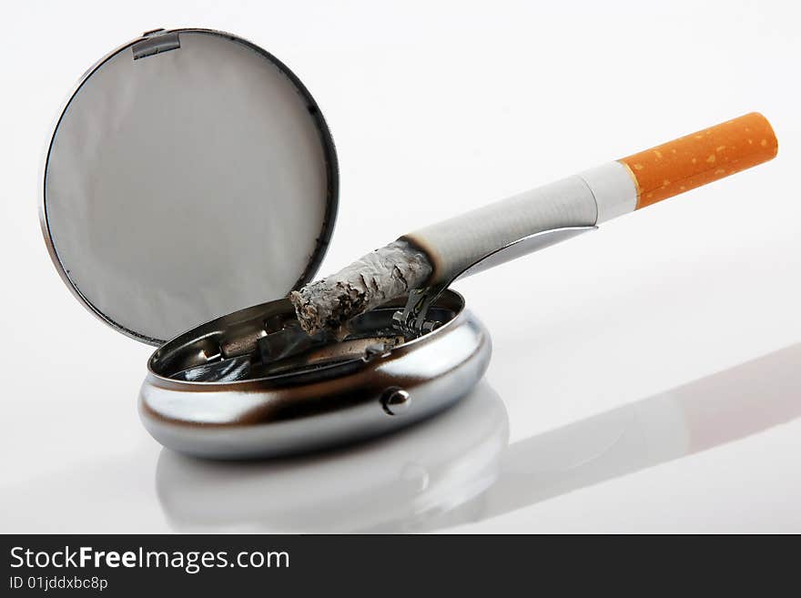 Ashtray with cigarette on white background