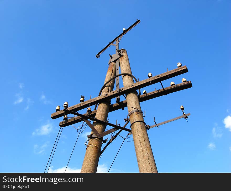 Old collapsing column of an electric main on background of blue sky. Old collapsing column of an electric main on background of blue sky