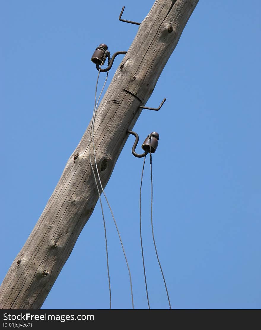 Old collapsing column of an electric main on  background of  blue sky. Old collapsing column of an electric main on  background of  blue sky