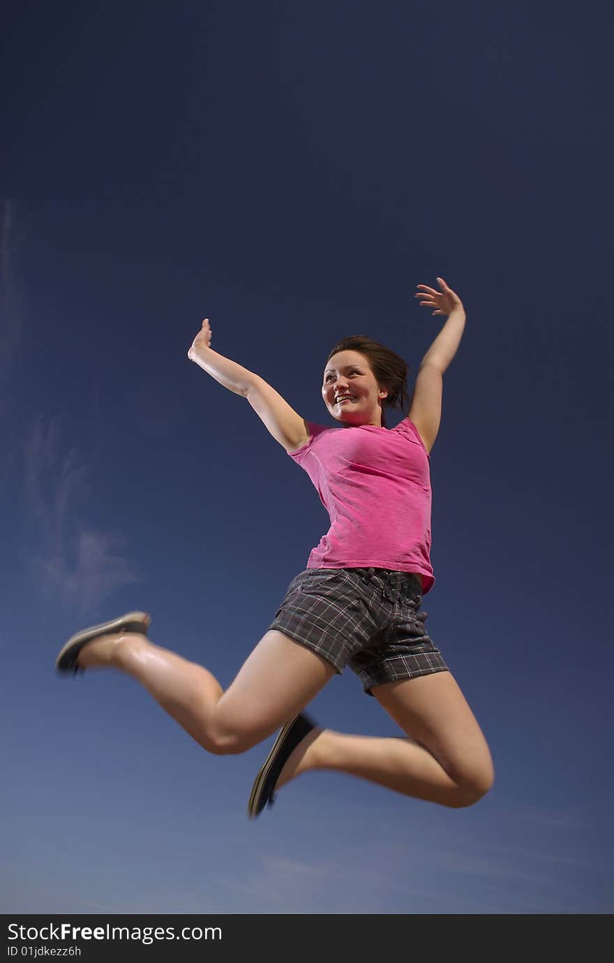 A teen girl leaps into a brilliant blue sky in a mood of shear exuberance. A teen girl leaps into a brilliant blue sky in a mood of shear exuberance.