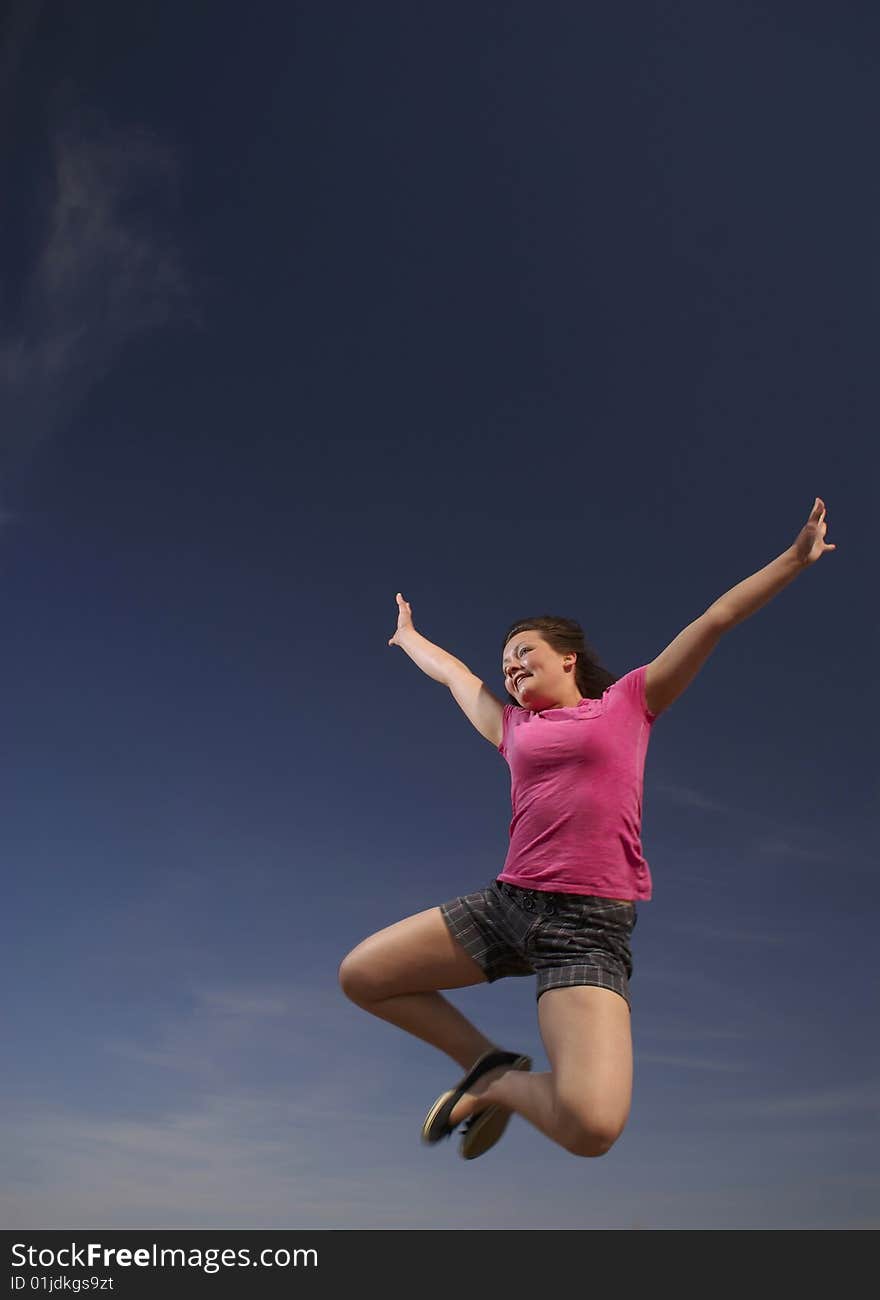 A teen girl leaps into a blue sky, celebrating life. A teen girl leaps into a blue sky, celebrating life.