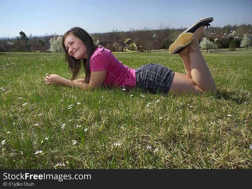 A teen daydreams on a spring day while lying in the grass and flowers on a sunny hillside. A teen daydreams on a spring day while lying in the grass and flowers on a sunny hillside.