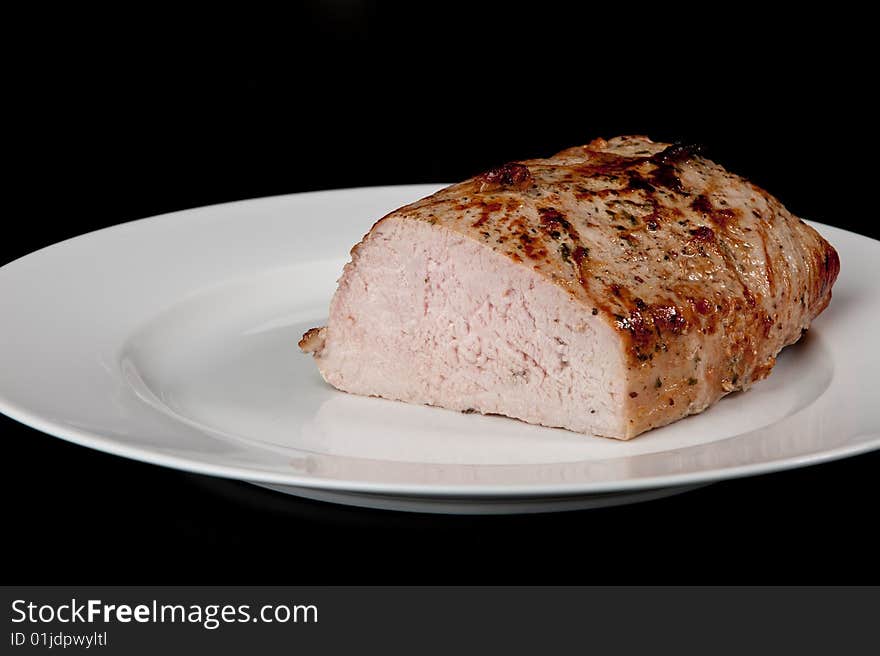 Image of a freshly cooked pork loin on a plate. Image of a freshly cooked pork loin on a plate