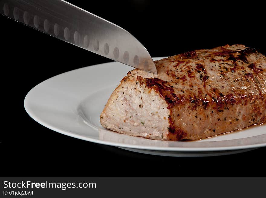 Image of a freshly cooked pork loin on a plate. Image of a freshly cooked pork loin on a plate