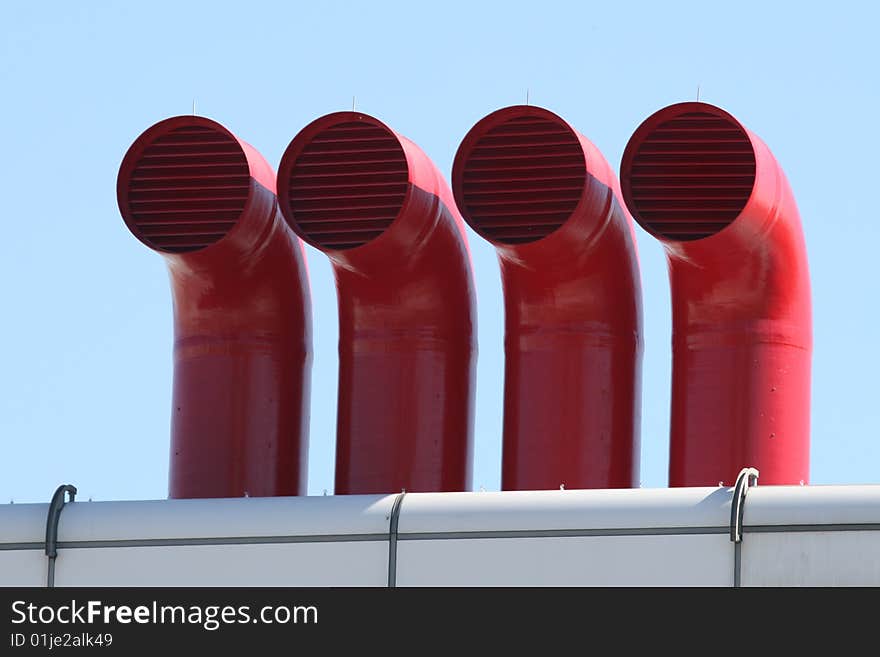 Four Stark Red Metal Factory Pipes on top of Industrial Complex