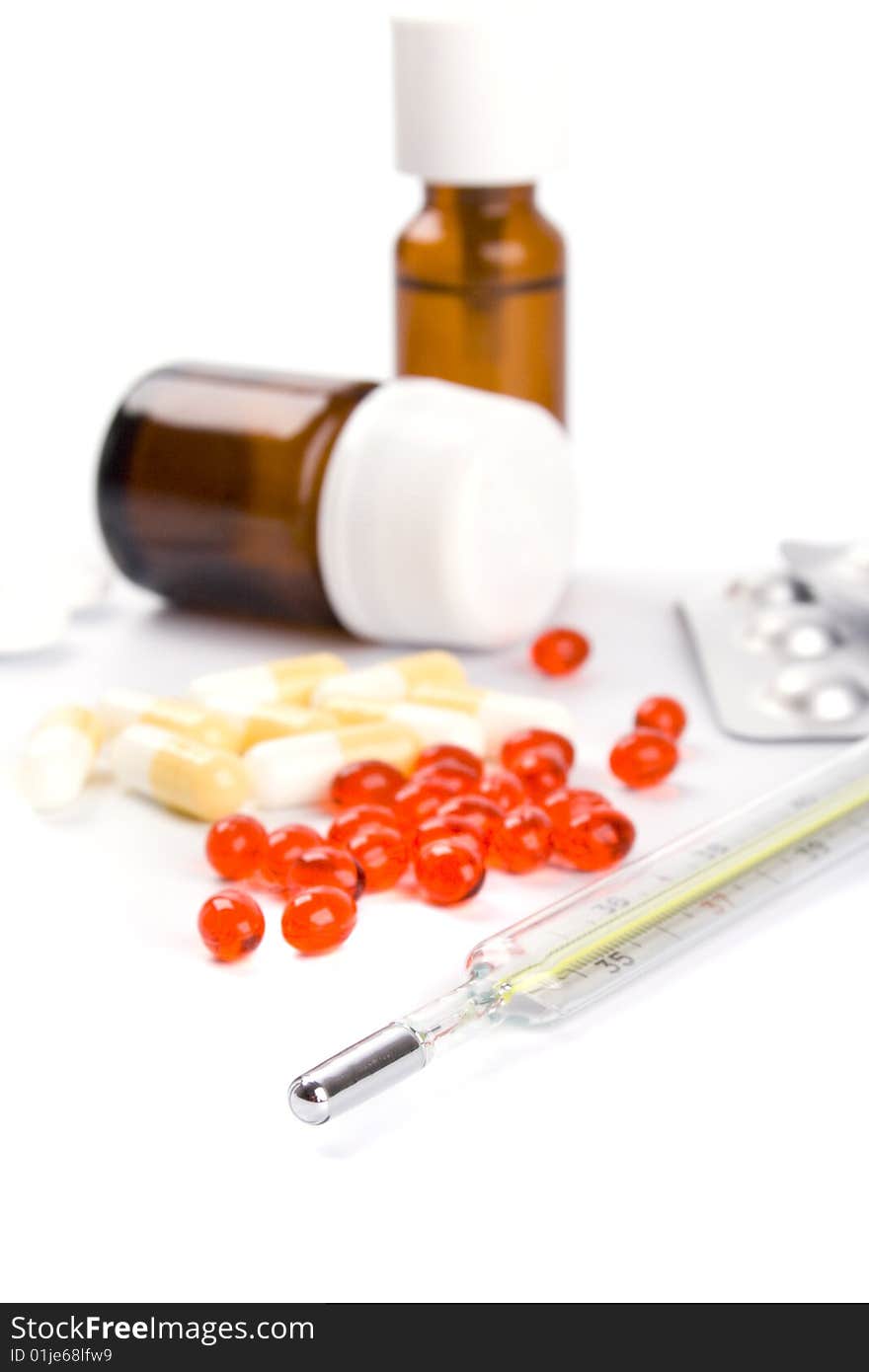 Thermometer and different pills closeup on white background