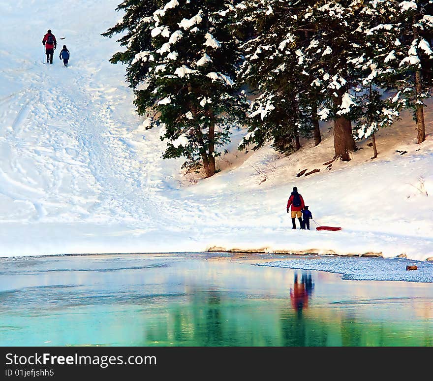 A family treks up a snowy hill for sledding fun. A family treks up a snowy hill for sledding fun