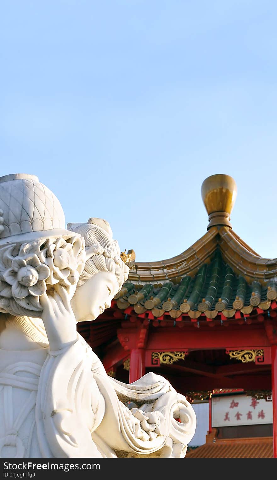 Traditional detail of a chinese female statute carrying a jug decorated with flowers.