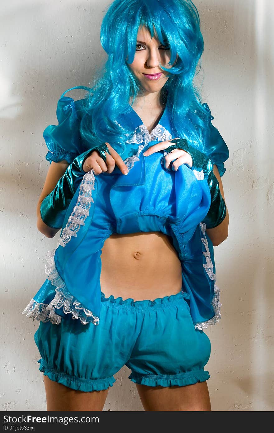 Woman wearing  blue dress and wig against the wall with fancy light pattern