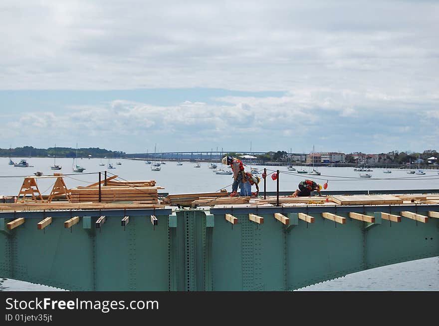 Workers working on a bridge over the ocean